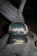 Green camo trucker hat with tan mesh back and white embroidered Miscellaneous logo